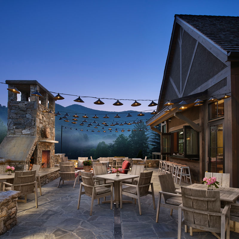 restaurant stone patio with string lights and light colored chair and table sets