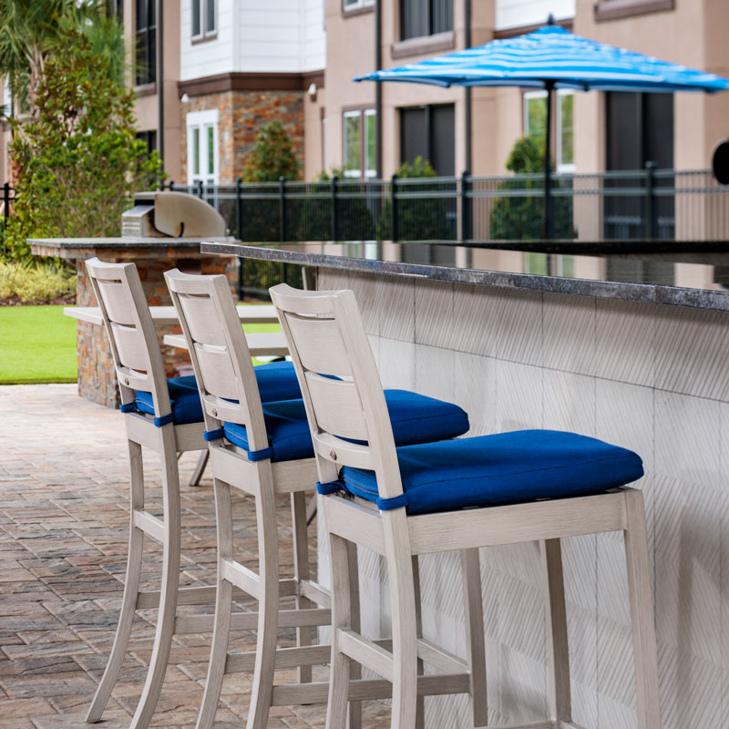 three high-top backed bar stools on an outdoor patio